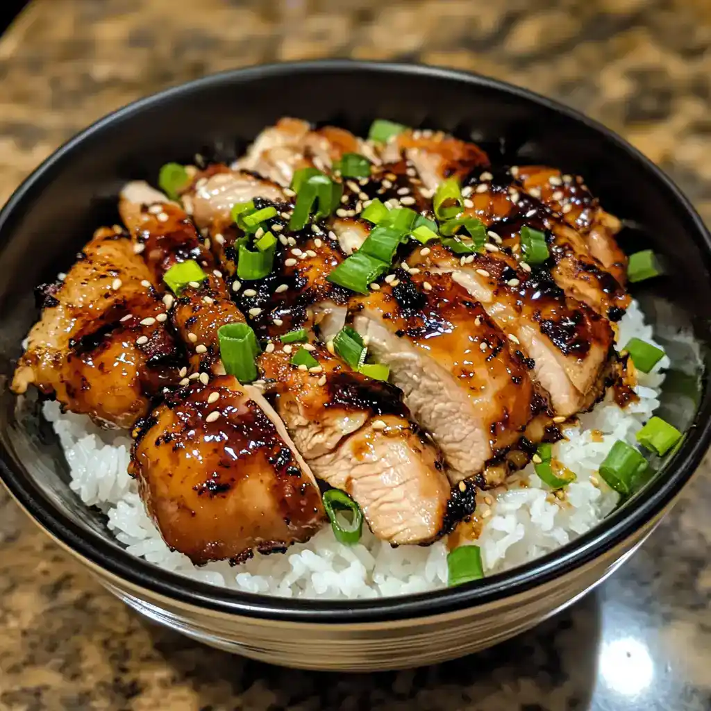 Juicy teriyaki chicken served over white rice, garnished with green onions and sesame seeds. Perfect for quick and delicious Asian-inspired meals.
