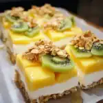 Fresh fruit cheesecake bars topped with kiwi, mango, and crunchy granola, perfect for summer desserts or healthy snacks, featured on Station Recipes.