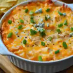 Creamy baked chicken dip with melted cheese, green onions, and blue cheese crumbles, perfect for game day or parties. Easy to make and full of flavor, served with chips or crackers.
