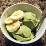 Sweet banana and green tea ice cream served in a bowl. Perfect for a refreshing dessert or snack. Made with natural ingredients and topped with fresh banana slices.