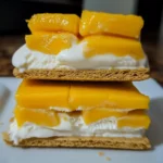 Sweet peach dessert bar with fresh peaches, creamy filling, and crisp graham cracker crust. Perfect for summer gatherings and easy to make, featuring a delightful combination of textures and flavors.