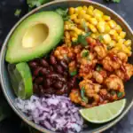 Fresh cauliflower buffalo wings served with avocado, black beans, corn, chopped red onions, and lime wedge in a colorful bowl. Perfect for healthy, flavorful snacks or meal ideas from Station Recipes.