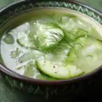 Refreshing cucumber dill soup with fresh herbs in a ceramic bowl, perfect summer cold appetizer.