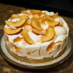 Sweet peach ice cream cake with caramel sauce and graham cracker crust, perfect for summer desserts.