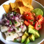 Fresh ceviche with diced fish, red onion, tomato, avocado, and lime, served with tortilla chips. A popular Mexican appetizer perfect for summer or any casual gathering.
