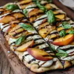 Fresh peach, mozzarella, basil, and balsamic glaze pizza on wooden serving board, gourmet summer appetizer, homemade Italian-style pizza with fresh ingredients, perfect for outdoor dining or family meals.