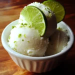 Lemon sorbet with lime slices and lime zest served in a white ramekin, showcasing a refreshing citrus dessert.