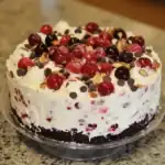 Fresh cherry and chocolate layered cake with whipped cream, chocolate chips, and toasted almond slices on top, perfect for dessert or special occasions.