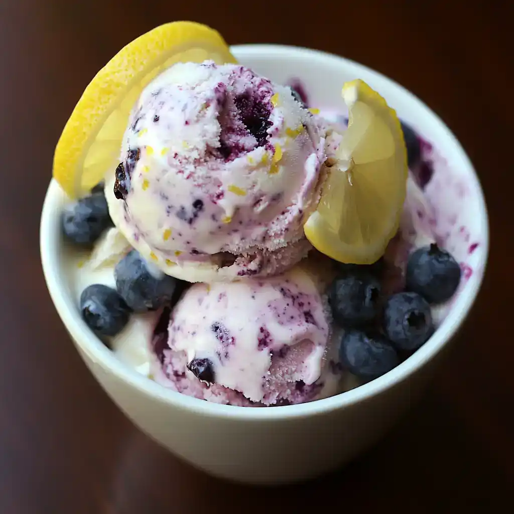 Sweet blueberry lemon ice cream topped with fresh blueberries and lemon slices, perfect for summer desserts and snack recipes.