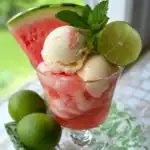 Refreshing watermelon lime ice cream float garnished with fresh mint and lime slices in a clear dessert glass. Perfect for summer desserts and fruit-based recipes.