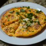 Fluffy scrambled eggs with cheese, herbs, and black pepper served on a white plate, perfect for breakfast or brunch. Easy to make and flavorful, ideal for quick morning meals.
