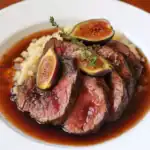 Juicy beef steak topped with fresh figs and herbs, served with creamy mashed potatoes and rich gravy, perfect for holiday dinners or special occasions.