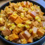 Sweet potato and corn hash in a black bowl, close-up, warm lighting.