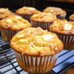 Fresh pineapple coconut muffins cooling on a wire rack, perfect for breakfast or snack. Delicious homemade muffin recipe featuring tropical flavors, moist crumb, and crumbly topping.