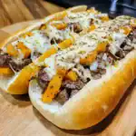 Savory steak and cheese sub sandwich with roasted peppers on a fresh hoagie bun, served on a wooden cutting board. Perfect for lunch or dinner, packed with melted cheese and tender beef.