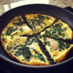 Savoury spinach and cheese frittata cooked in a skillet, perfect for breakfast or brunch, featuring fresh spinach, eggs, and cheese.