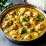 Rich chicken curry in a stainless steel bowl garnished with fresh cilantro, showcasing flavorful Indian-inspired cuisine perfect for dinner or meal prep.