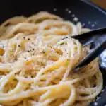 Creamy garlic parmesan pasta with freshly ground black pepper, served in a black skillet. Perfect comfort food recipe from Station Recipes.