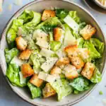 Crisp Caesar salad with romaine lettuce, crunchy croutons, shaved Parmesan cheese, and black pepper in a rustic bowl, perfect for quick lunch or dinner.