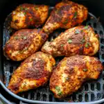 Juicy, perfectly seasoned baked chicken thighs with crispy skin, garnished with fresh herbs, cooked in an air fryer for easy and flavorful meal prep.