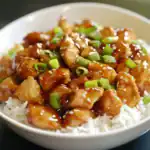 Savory chicken stir-fry served over white rice, topped with green onions and sesame seeds, glazed in a flavorful brown sauce, perfect for quick dinner recipes.