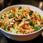 Fresh Thai chicken lettuce wraps in a white bowl with shredded carrots, chopped cilantro, sliced almonds, and crispy cabbage. Perfect for a healthy, flavorful appetizer or light lunch inspired by Station Recipes.