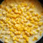 Buttered corn with black pepper in a creamy sauce, close-up image.