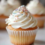 Delicious vanilla cupcake topped with swirled buttercream frosting and colorful sprinkles, perfect for celebrations and dessert lovers.