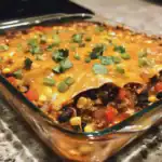 Cheesy taco casserole with ground beef, black beans, corn, and fresh cilantro in a glass baking dish. Perfect for a quick and flavorful dinner, combining Mexican-inspired ingredients for a delicious family meal.