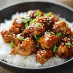 Sweet and savory Asian-style chicken bites served over white rice, topped with green onions and sesame seeds, coated in a flavorful sticky sauce. Perfect for quick dinner recipes.