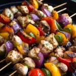 Grilled chicken and vegetable skewers with colorful peppers, onions, and mushrooms on a barbecue grill. Perfect for summer cookouts and easy delicious recipes from Station Recipes.