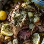 Juicy roasted prime rib with garlic and herbs, served with lemon wedges and roasted garlic for a flavorful, tender beef dish perfect for special occasions or family dinners.