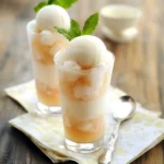 Creamy vanilla ice cream float with caramel drizzle, garnished with fresh mint leaves in tall glass, perfect for summer desserts.