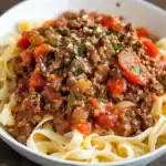 Savory beef and tomato sauce over pasta, close-up, Station Recipes, easy homemade pasta recipe, classic Italian beef bolognese, flavorful beef ragù, comforting Italian dinner.