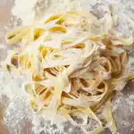 Fresh homemade fettuccine pasta with flour dusting, perfect for delicious Italian dishes.
