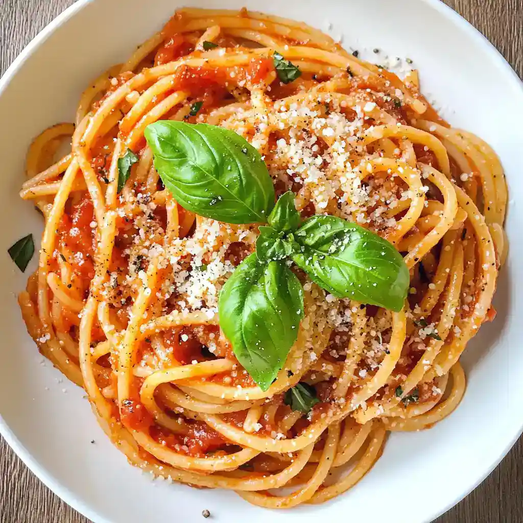 Golden Spaghetti Marinara with Fresh Basil, Parmesan, and Olive Oil on White Plate—Classic Italian Pasta Recipe from Station Recipes.