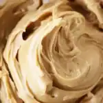 Creamy peanut butter frosting close-up, smooth and luscious texture, perfect for decorating cupcakes and cakes, ideal for homemade dessert recipes.