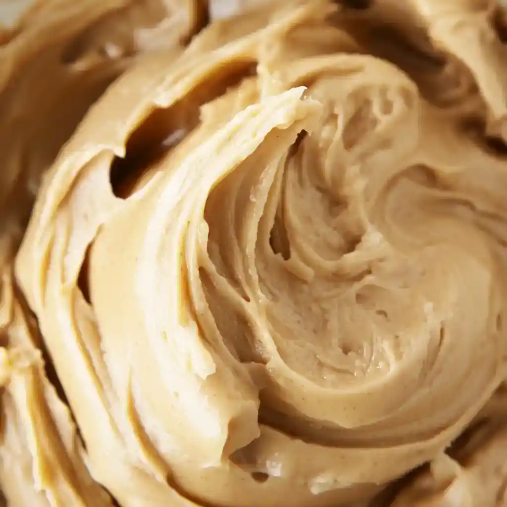 Creamy peanut butter frosting close-up, smooth and luscious texture, perfect for decorating cupcakes and cakes, ideal for homemade dessert recipes.