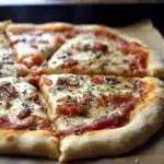 Hot cheesy pepperoni pizza topped with herbs and cooked to perfection on a wooden pizza peel.