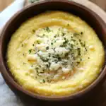 Creamy corn chowder in a rustic wooden bowl garnished with cheese and herbs. Delicious, comforting soup recipe perfect for cozy meals and easy family dinners.
