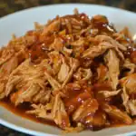 Shredded chicken with barbecue sauce on a white plate, tender and flavorful, perfect for sandwiches or wraps. A delicious homemade shredded chicken recipe for quick and easy meals.