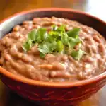 Creamy pinto beans with fresh cilantro garnish in a rustic bowl, comforting homemade bean dish, perfect for cozy meals or side dishes, from Station Recipes.