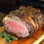 Juicy oven-roasted beef tenderloin wrapped in bacon on a wooden cutting board with herbs, perfect for special occasions and family dinners.