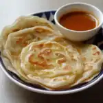 Crispy Indian paratha served with spicy chutney, ideal for breakfast or lunch, featuring flaky layers and a golden-brown crust. Perfect for enjoying with dips or curries.