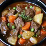 Hearty beef stew with tender potatoes, carrots, peas, and savory herbs in rich broth, perfect for comforting family dinners and meal prep.