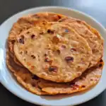 Flame grilled flatbreads with a crispy, slightly charred exterior on a white plate, perfect for enjoying Indian or Middle Eastern cuisine.