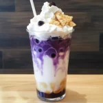 Creamy blueberry bubble tea with whipped cream and crunchy toppings, served in a tall glass. Refreshing and delicious bubble milk tea perfect for summer or any time.