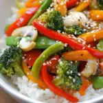 Fresh vegetable stir-fry with broccoli, red bell peppers, carrots, mushrooms, and sesame seeds served over white rice — healthy, colorful, and easy to make at home.