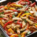 Brightly colored stir-fry chicken with red, yellow, and green bell peppers garnished with cilantro for a healthy meal. Perfect for quick dinner recipes and meal prep.