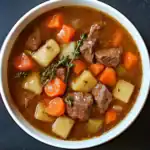 Rich, flavorful beef stew with tender chunks of beef, carrots, potatoes, and celery, garnished with fresh thyme for a comforting meal. Perfect for cold days or family dinners.